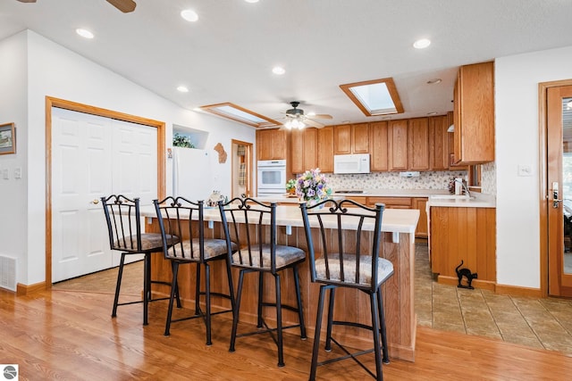 5449 E Shore Dr NE, Kalkaska, MI 49646 - kitchen featuring white appliances, ceiling fan, light countertops, light wood finished floors, and tasteful backsplash