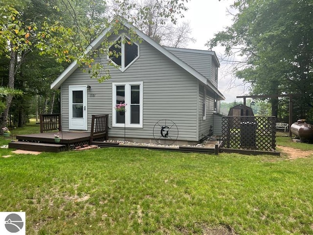 rear view of house with a lawn and a wooden deck