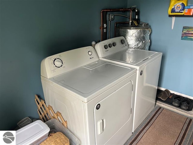 clothes washing area featuring washing machine and clothes dryer, laundry area, and water heater