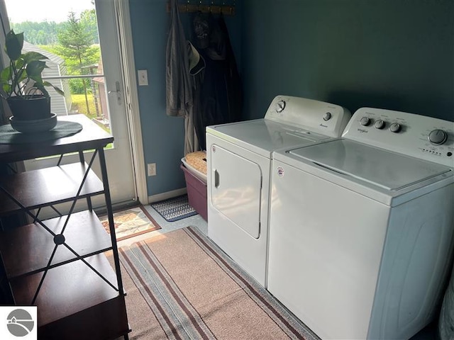 clothes washing area with separate washer and dryer and baseboards