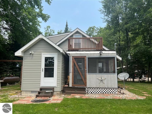 rear view of house featuring a lawn, a balcony, a sunroom, and entry steps