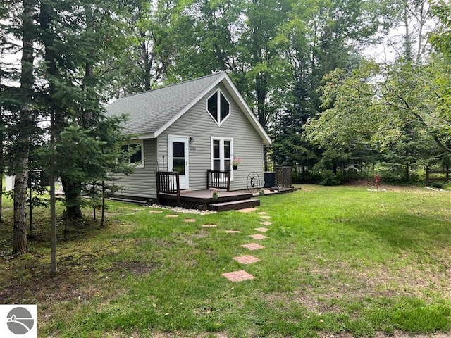 exterior space with a wooden deck, a shingled roof, and a front lawn