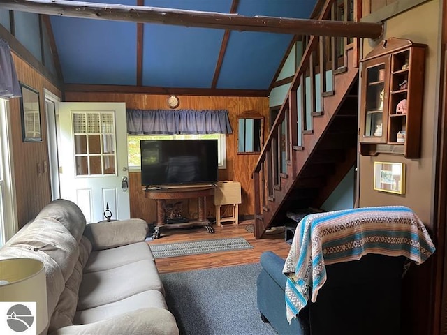 living room featuring wood finished floors, vaulted ceiling, and stairway
