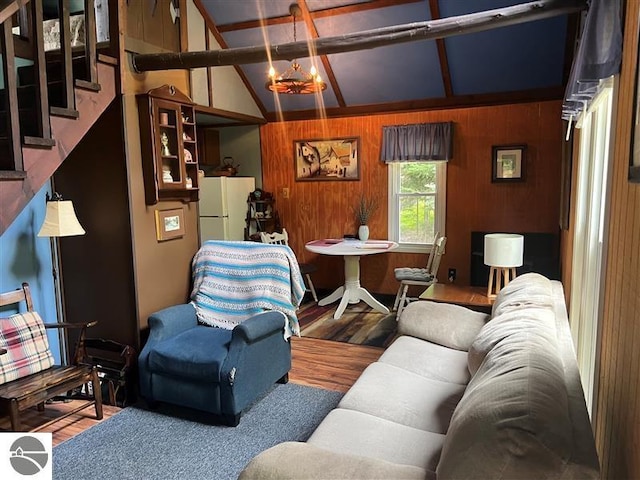 living area featuring stairway, lofted ceiling with beams, wooden walls, and wood finished floors
