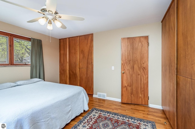 bedroom featuring baseboards, ceiling fan, light wood-style flooring, and visible vents