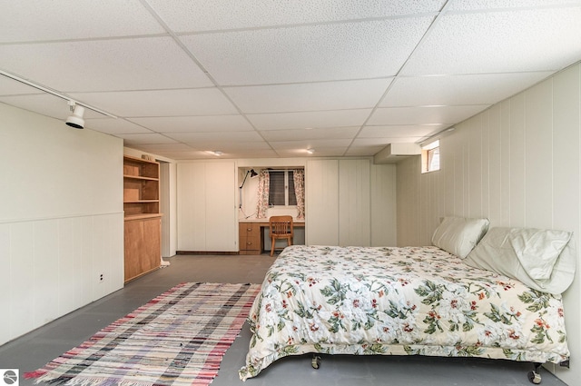 bedroom featuring wooden walls and a drop ceiling