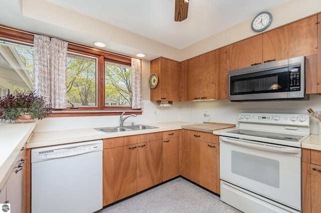 kitchen with a sink, light countertops, brown cabinets, and white appliances