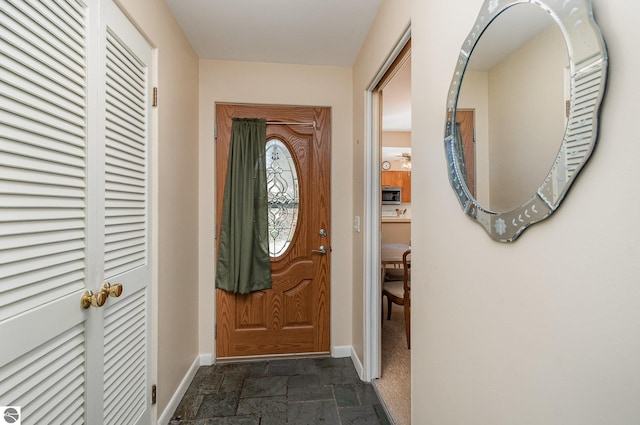 doorway with baseboards and stone tile flooring