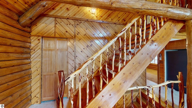 stairs with lofted ceiling with beams, wood ceiling, rustic walls, and tile patterned floors