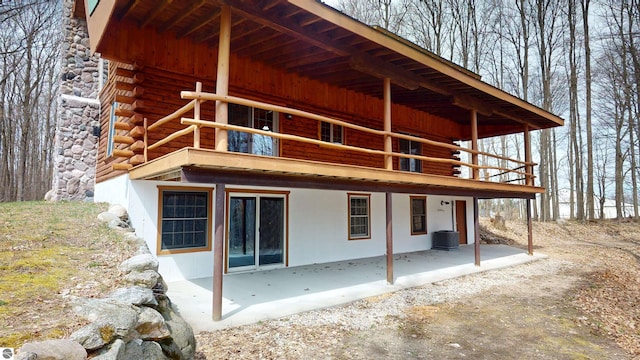 back of house with central AC, log exterior, a balcony, and a patio area