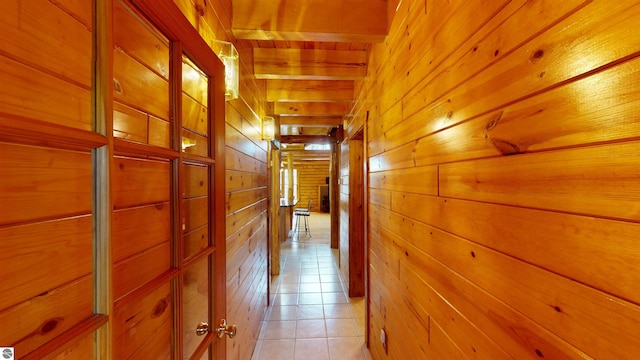 hallway with wooden walls and light tile patterned floors
