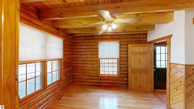 unfurnished room featuring rustic walls, ceiling fan, beamed ceiling, and light wood-style flooring