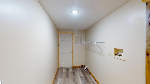 clothes washing area featuring laundry area, baseboards, light wood-style floors, a textured ceiling, and washer hookup