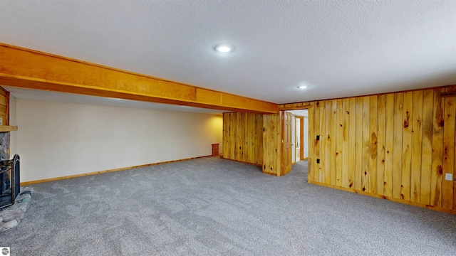 unfurnished living room with carpet flooring, wooden walls, a fireplace, recessed lighting, and baseboards