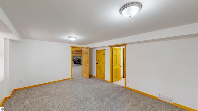 finished below grade area with baseboards, light carpet, and visible vents