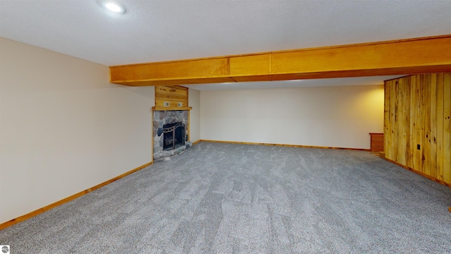 unfurnished living room with wooden walls, baseboards, a fireplace, and carpet flooring
