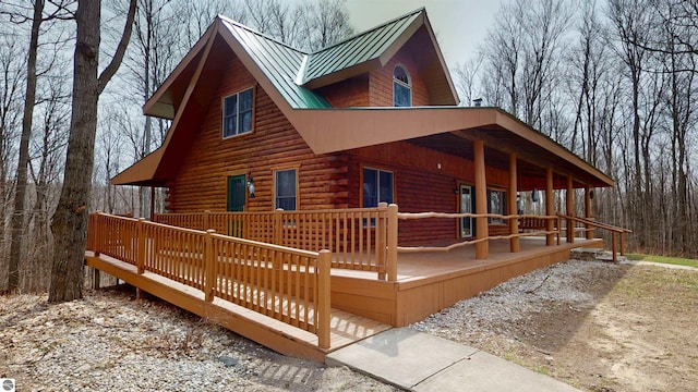 exterior space featuring a standing seam roof, log exterior, a porch, and metal roof