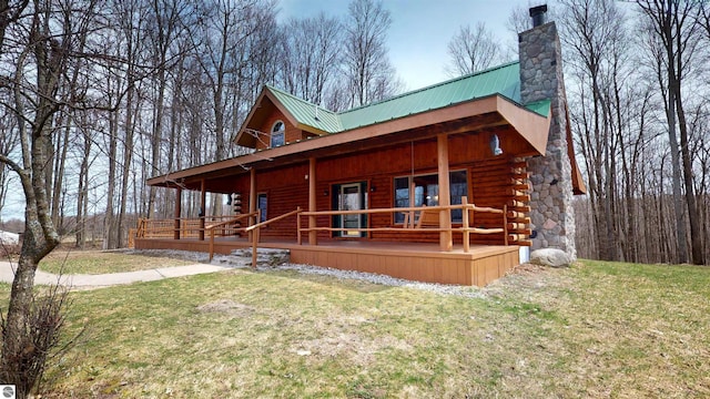 log cabin featuring covered porch, a chimney, and a front lawn