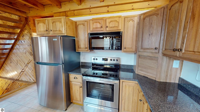 kitchen with dark stone counters, beam ceiling, appliances with stainless steel finishes, and light tile patterned floors