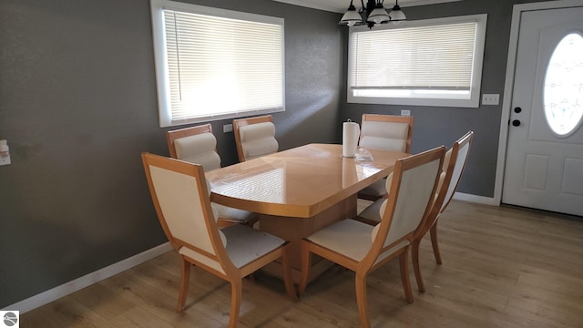 dining area featuring baseboards, light wood-style flooring, crown molding, and a chandelier