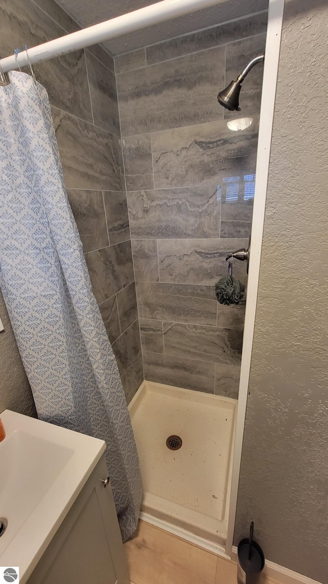 bathroom featuring a textured wall, a shower stall, and vanity