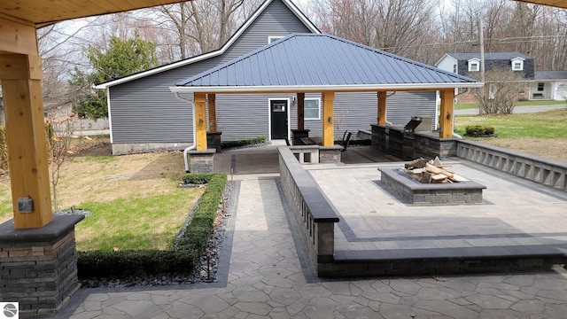 exterior space with a lawn, a patio, an outdoor fire pit, and metal roof