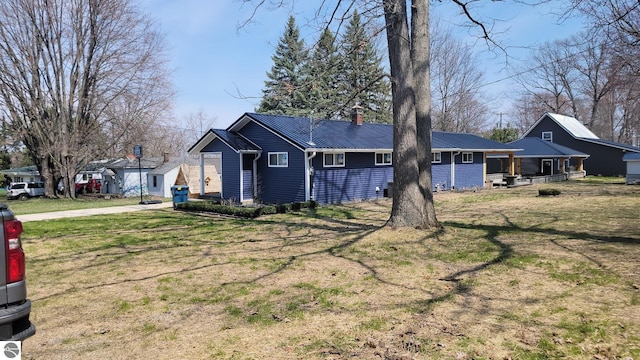 view of front facade with a chimney, metal roof, and a front lawn