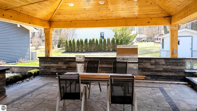 view of patio / terrace with a gazebo, outdoor dining area, an outbuilding, and a storage unit