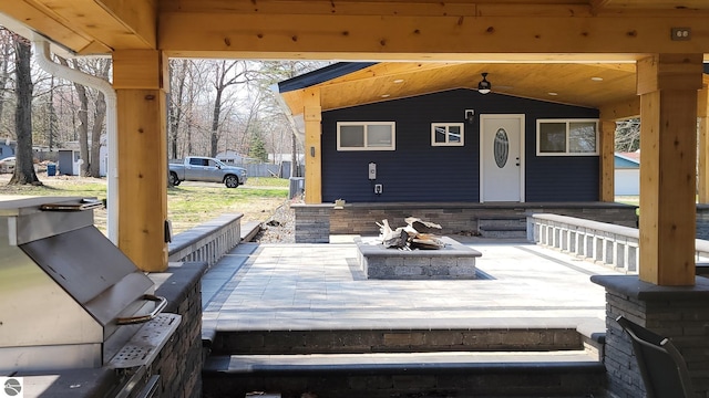 wooden terrace featuring ceiling fan and an outdoor fire pit