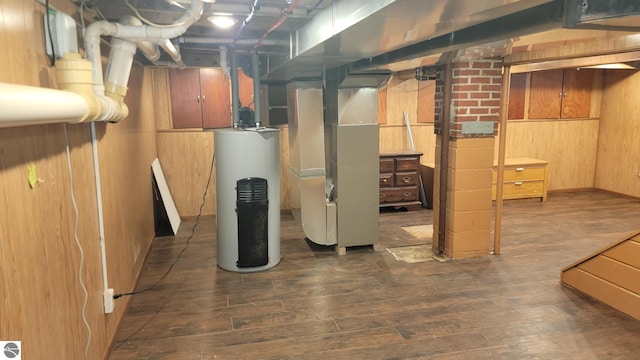 basement with wooden walls, heating unit, hardwood / wood-style flooring, and gas water heater