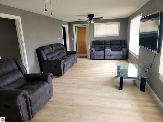 living room featuring baseboards, ceiling fan, and light wood-style flooring