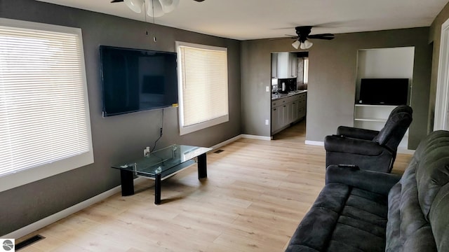 living area with ceiling fan, a healthy amount of sunlight, and light wood-style flooring