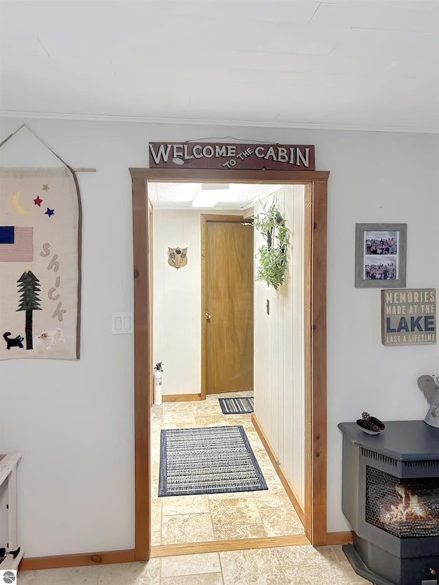 interior space featuring crown molding, baseboards, and a wood stove
