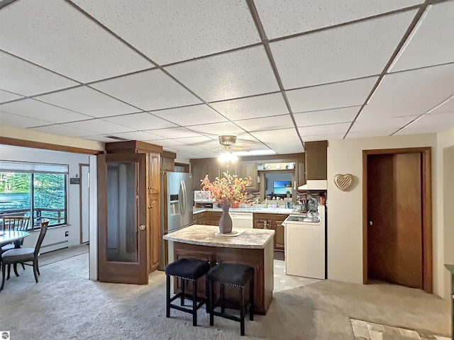 kitchen featuring light colored carpet, light countertops, range, a drop ceiling, and a kitchen island