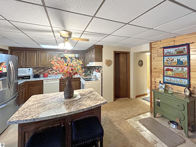 kitchen with light colored carpet, light countertops, under cabinet range hood, and white appliances
