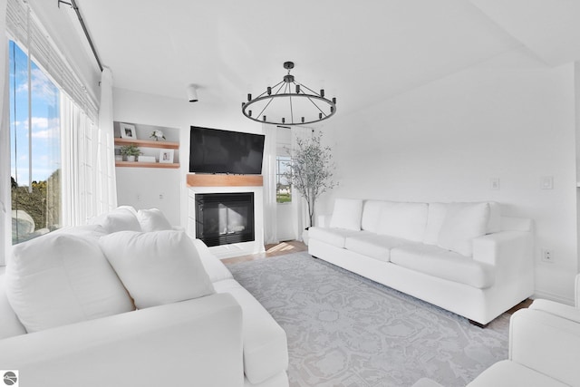 living area with a glass covered fireplace, wood finished floors, and a chandelier