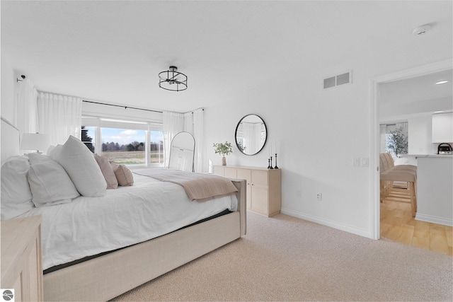 bedroom featuring baseboards, light colored carpet, and visible vents