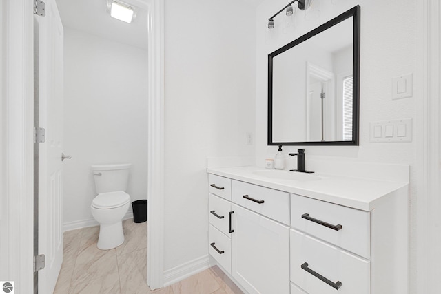 bathroom with vanity, baseboards, and toilet