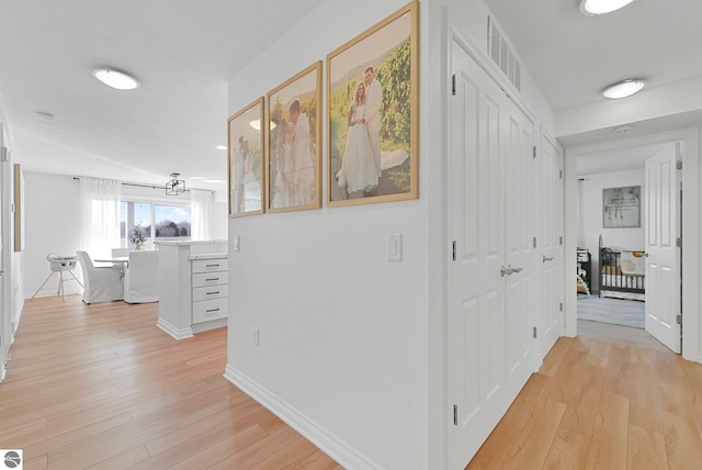 hallway with baseboards, visible vents, and light wood-style flooring