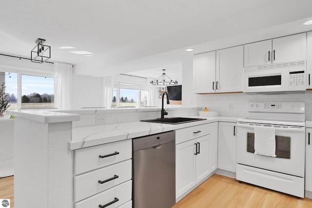 kitchen featuring white appliances, white cabinetry, decorative backsplash, and a sink