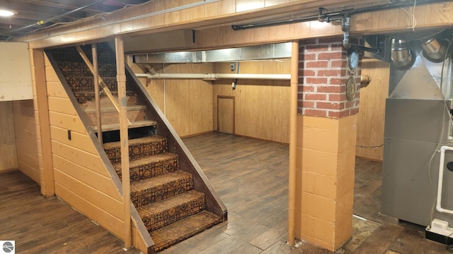 unfinished basement with wooden walls, stairs, and wood finished floors