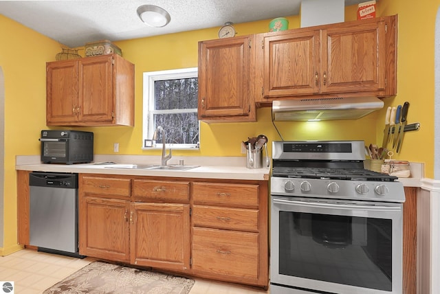 9916 S M-37, Buckley, MI 49620 - kitchen with brown cabinets, appliances with stainless steel finishes, a sink, light countertops, and under cabinet range hood