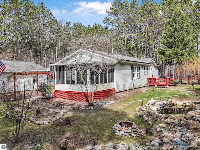 9916 S M-37, Buckley, MI 49620 - view of front facade featuring a wooden deck, a sunroom, an outdoor fire pit, and a front yard