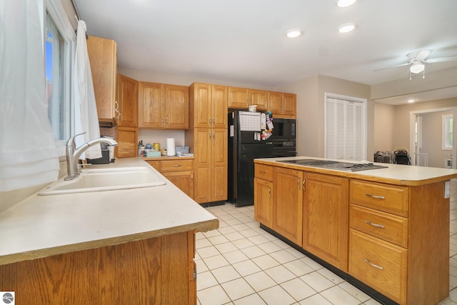 kitchen with a sink, light countertops, a kitchen island, and black appliances