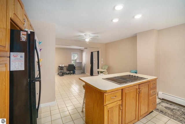 kitchen featuring freestanding refrigerator, a kitchen island, light tile patterned flooring, ceiling fan, and stovetop with downdraft