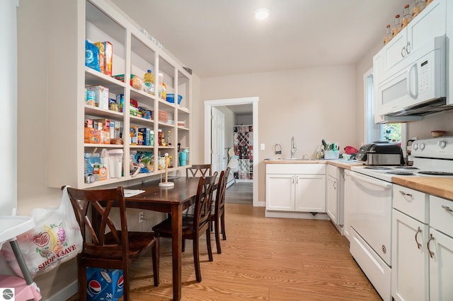 kitchen with a sink, light wood-style floors, white appliances, white cabinetry, and butcher block counters