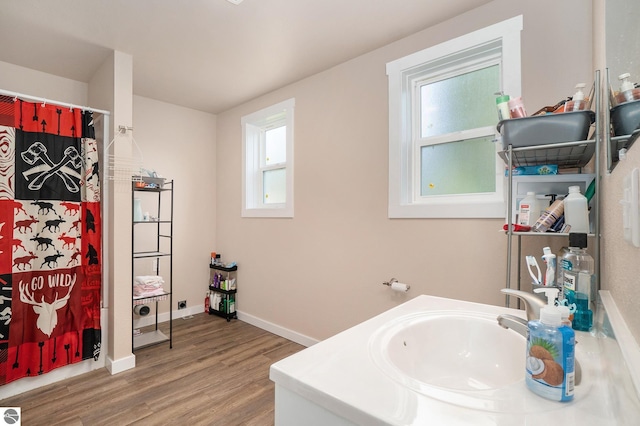bathroom featuring baseboards, curtained shower, a wealth of natural light, and wood finished floors