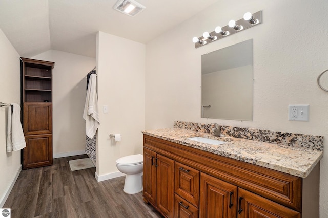 full bathroom with vanity, toilet, wood finished floors, vaulted ceiling, and visible vents