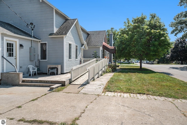 view of side of property with a lawn and a shingled roof