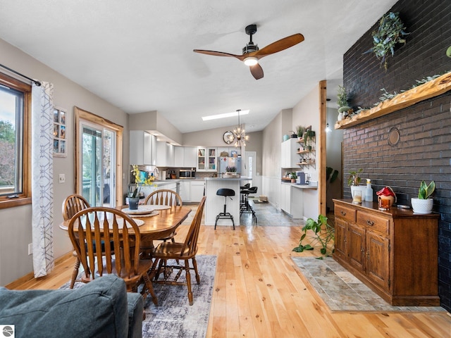 431 E Bittner Ave, Reed City, MI 49618 - dining room featuring baseboards, light wood-style flooring, ceiling fan with notable chandelier, and lofted ceiling
